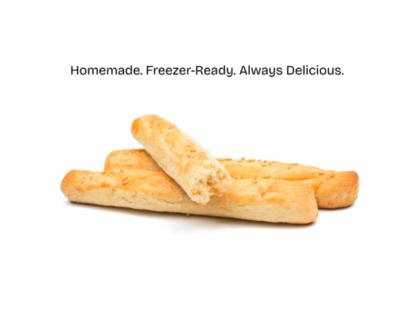 Homemade breadsticks on a parchment-lined baking sheet, brushed with melted butter and sprinkled with herbs, ready to be baked or frozen for later.